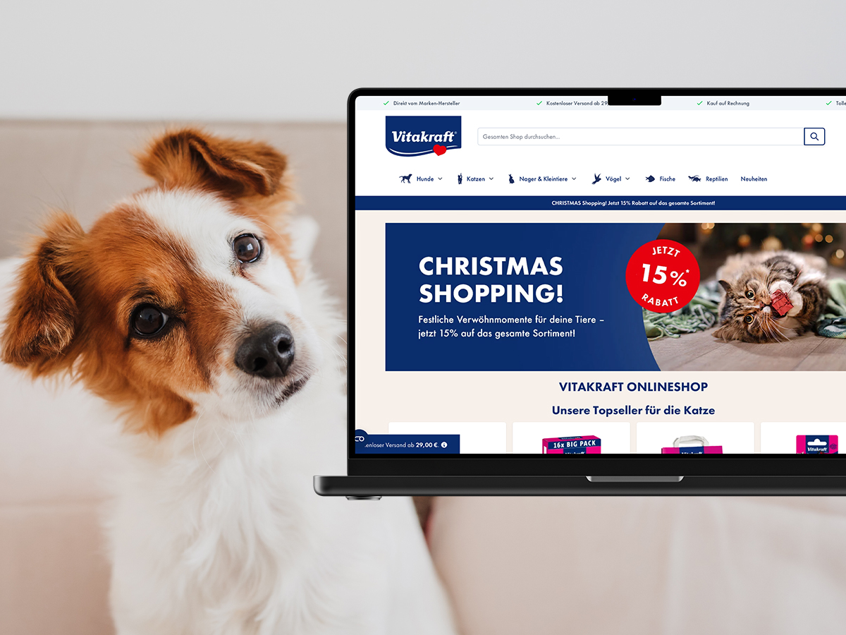 Laptop mit Vitakraft Shop offen und einem Hund daneben